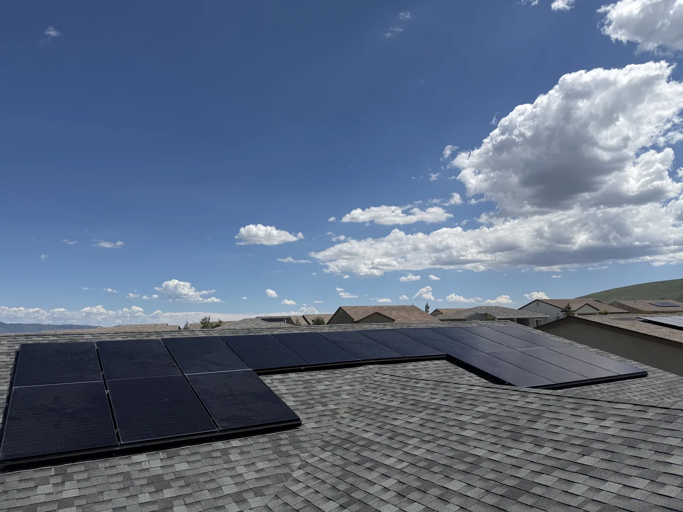 Solar panels installed across a home roof beneath a blue sky